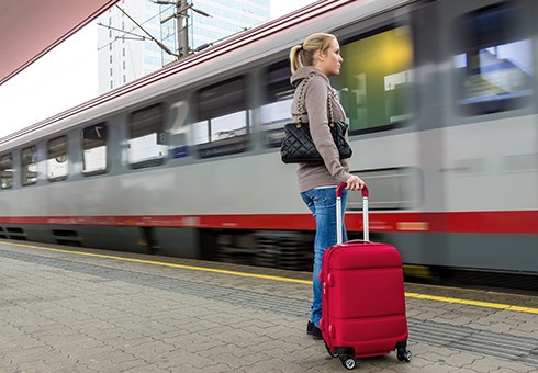 Frau mit Reisekoffer am Bahnhof